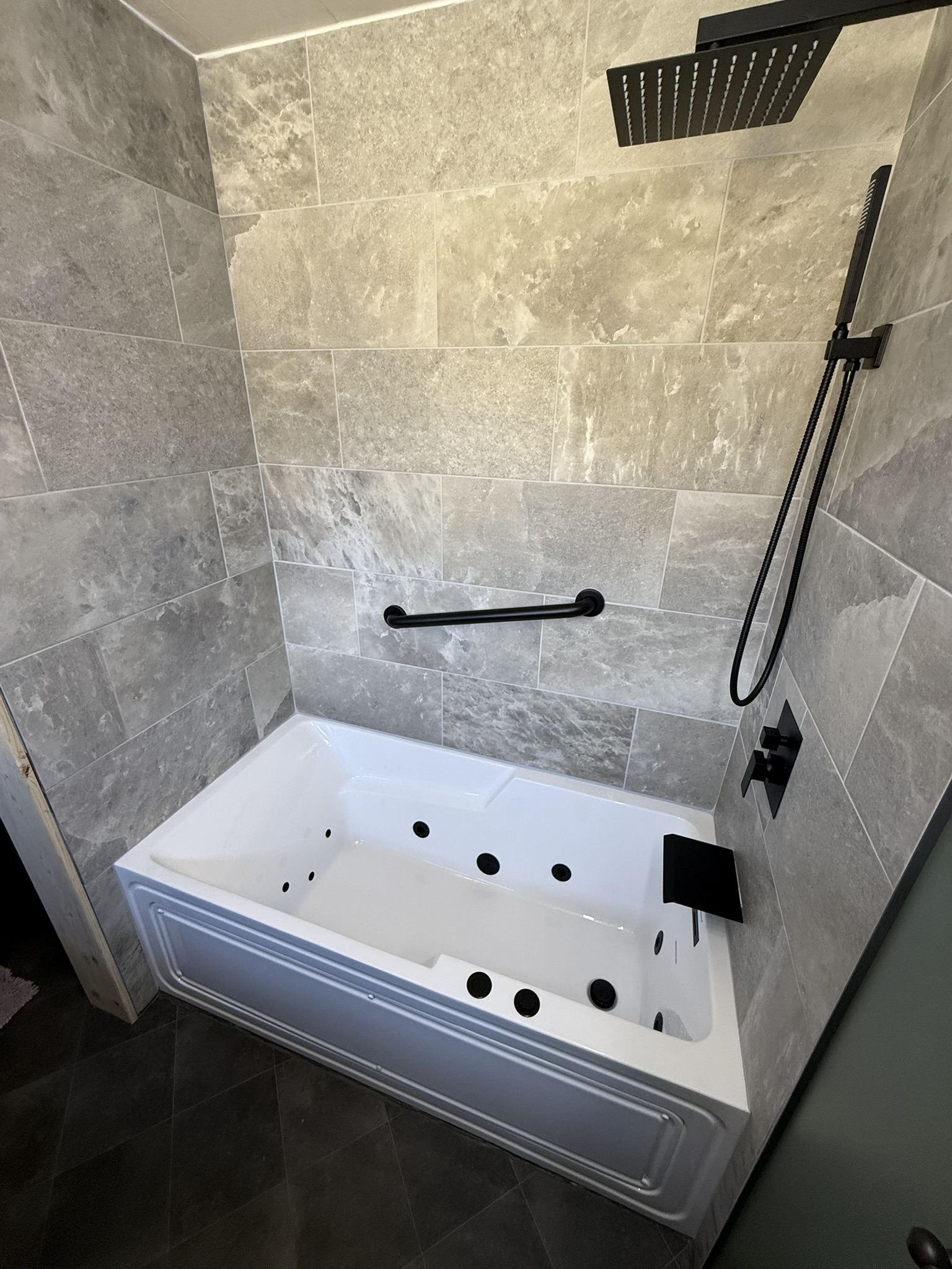 Jetted soaking tub with full tile surround and matte black fixtures
