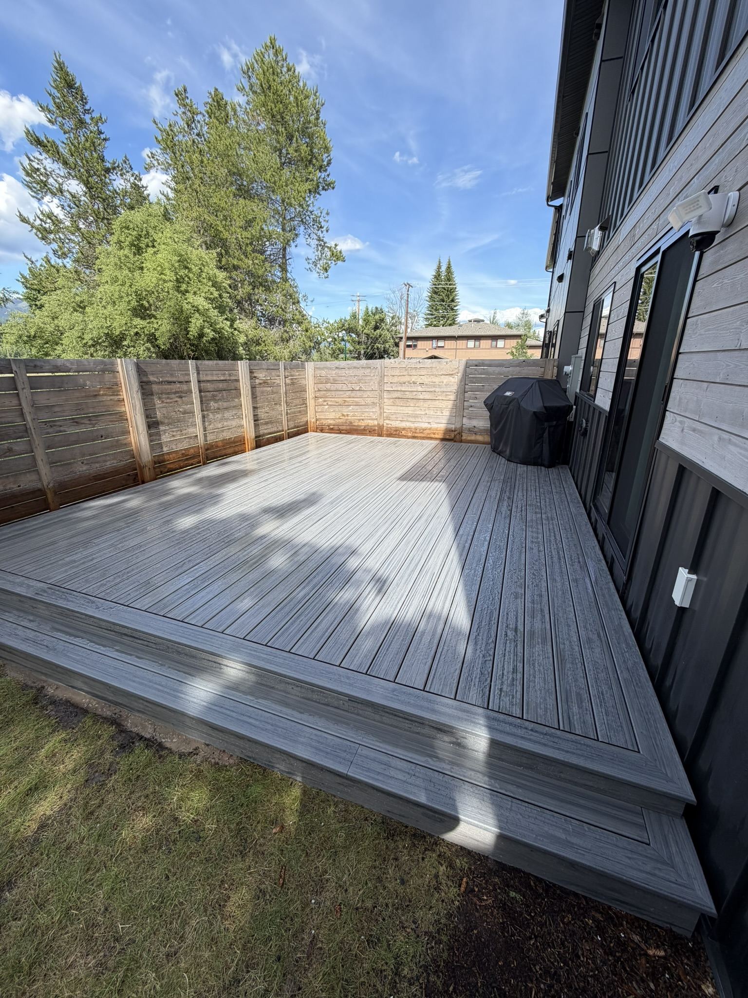 New gray composite deck along the side of a modern home