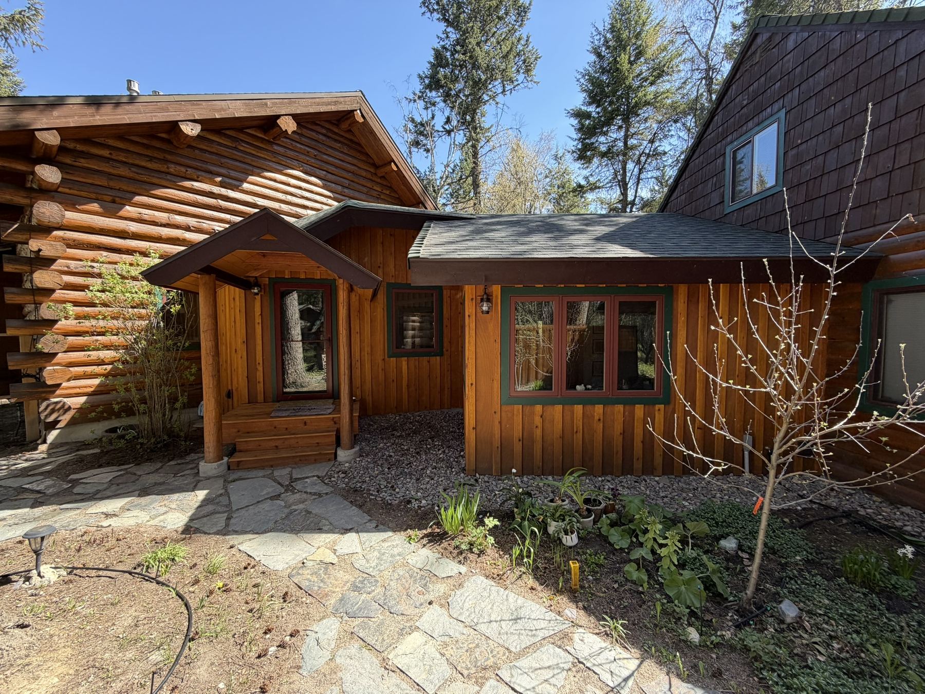 Log home entry with timber porch and flagstone walkway